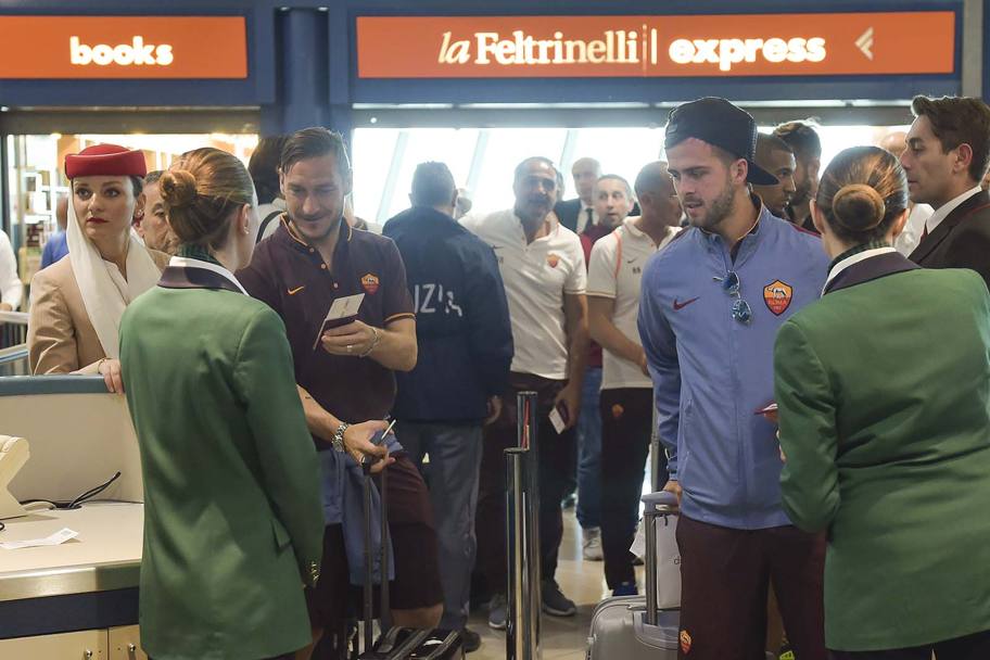 Francesco Totti al check-in, sorridente: a breve dovrebbe arrivare l&#39;annuncio del suo rinnovo di contratto. Foto asroma.it